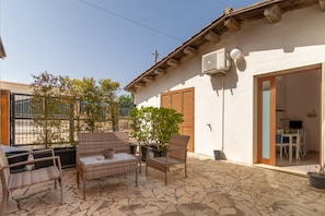 Une terrasse dotée de meubles en osier, de plantes en pot et d’un sol en pierre.