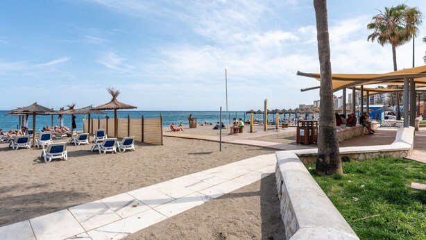 A beach with sun loungers, umbrellas, and a covered seating area. - Apartment 'Apartamento Postal' with Balcony, Wi-Fi and Air Conditioning (Fuengirola)