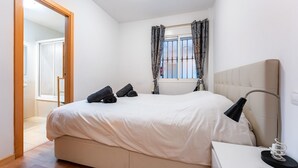 A bedroom with a bed, bedside lamp, and a window with curtains. - Apartment 'Apartamento Postal' with Balcony, Wi-Fi and Air Conditioning (Fuengirola)