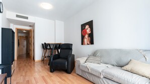 A living room with a sofa, a chair, a table, and a painting on the wall. - Apartment 'Apartamento Postal' with Balcony, Wi-Fi and Air Conditioning (Fuengirola)