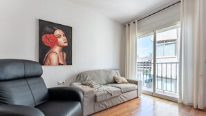 A living room with a black leather sofa, a grey sofa with cushions, a painting on the wall, and a balcony with a view. - Apartment 'Apartamento Postal' with Balcony, Wi-Fi and Air Conditioning (Fuengirola)
