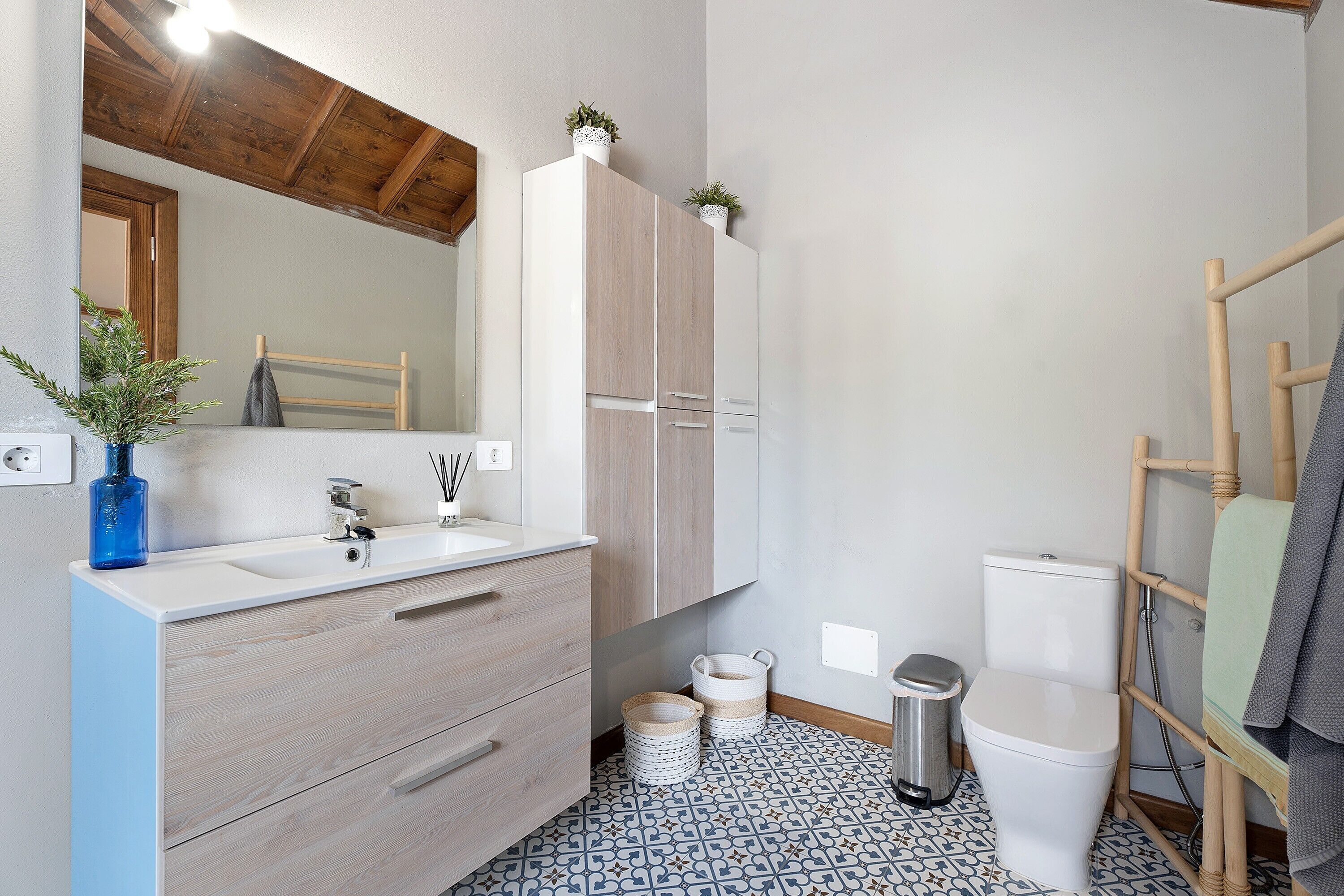 Un baño con tocador de madera, lavamanos, inodoro y espejo.