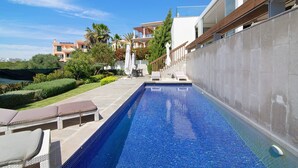 A swimming pool with lounge chairs, a clear blue sky, and modern buildings in the background. - Villa "Sweet Home Albufeira" with Private Pool, 2 Private Terraces & Wi-Fi (Albufeira)