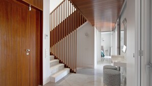 A modern interior with a wooden staircase, a marble floor, and a seating area with a white and grey pattern. - Villa "Sweet Home Albufeira" with Private Pool, 2 Private Terraces & Wi-Fi (Albufeira)