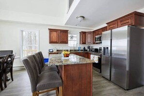 A modern kitchen with granite countertops, dark wood cabinets, stainless steel appliances, and a bar seating area. - Pocono’s Cabin w/Hot tub, Firepit, Game room,Lakes (Pocono Lake)
