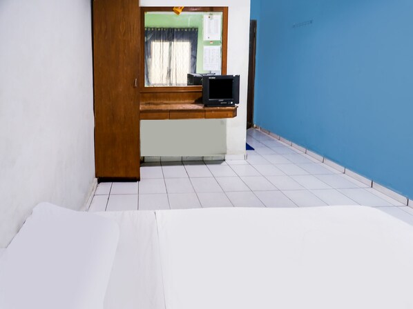 Una habitación con un escritorio de madera, una computadora y un ventanal con cortinas.