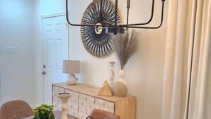 Un comedor con una mesa de madera, una araña y un adorno en la pared.