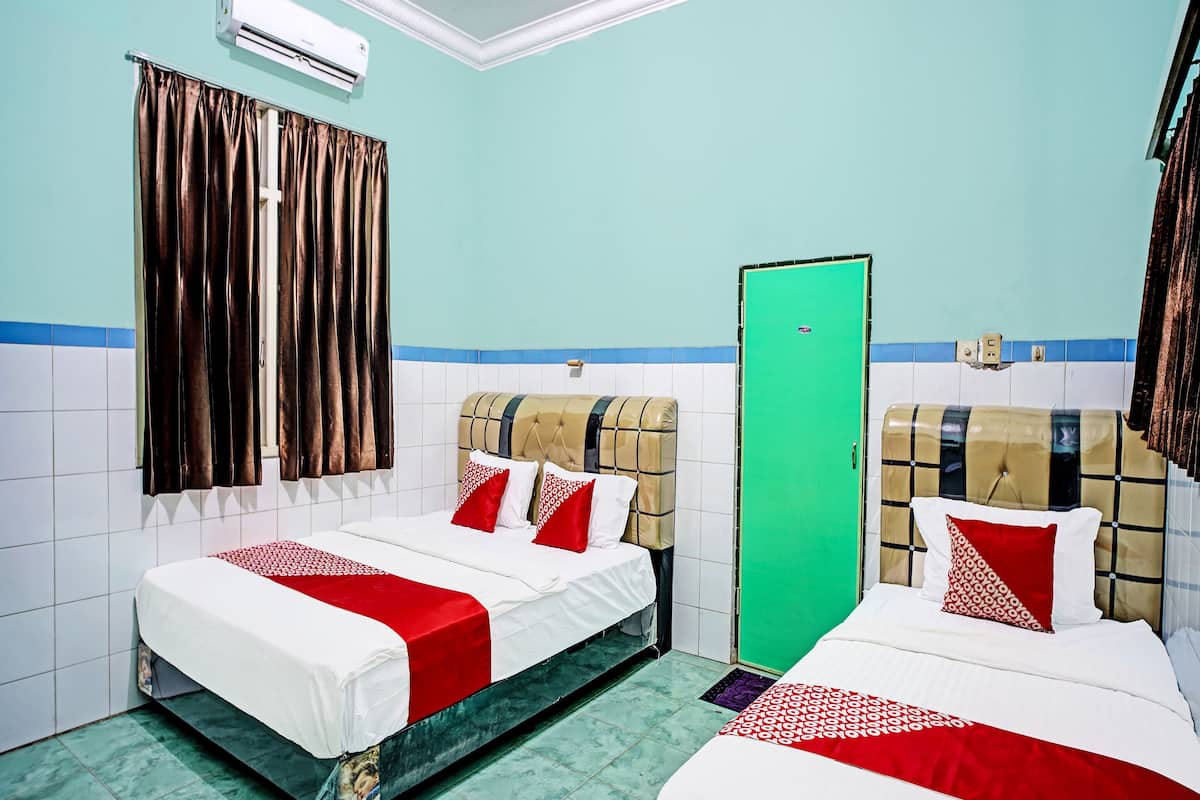 Une chambre d’hôtel avec deux lits, une porte verte et un appareil de climatisation.