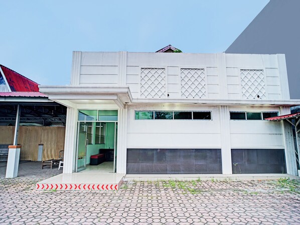 A two-story building with a garage door, a covered entrance, and a tiled patio.