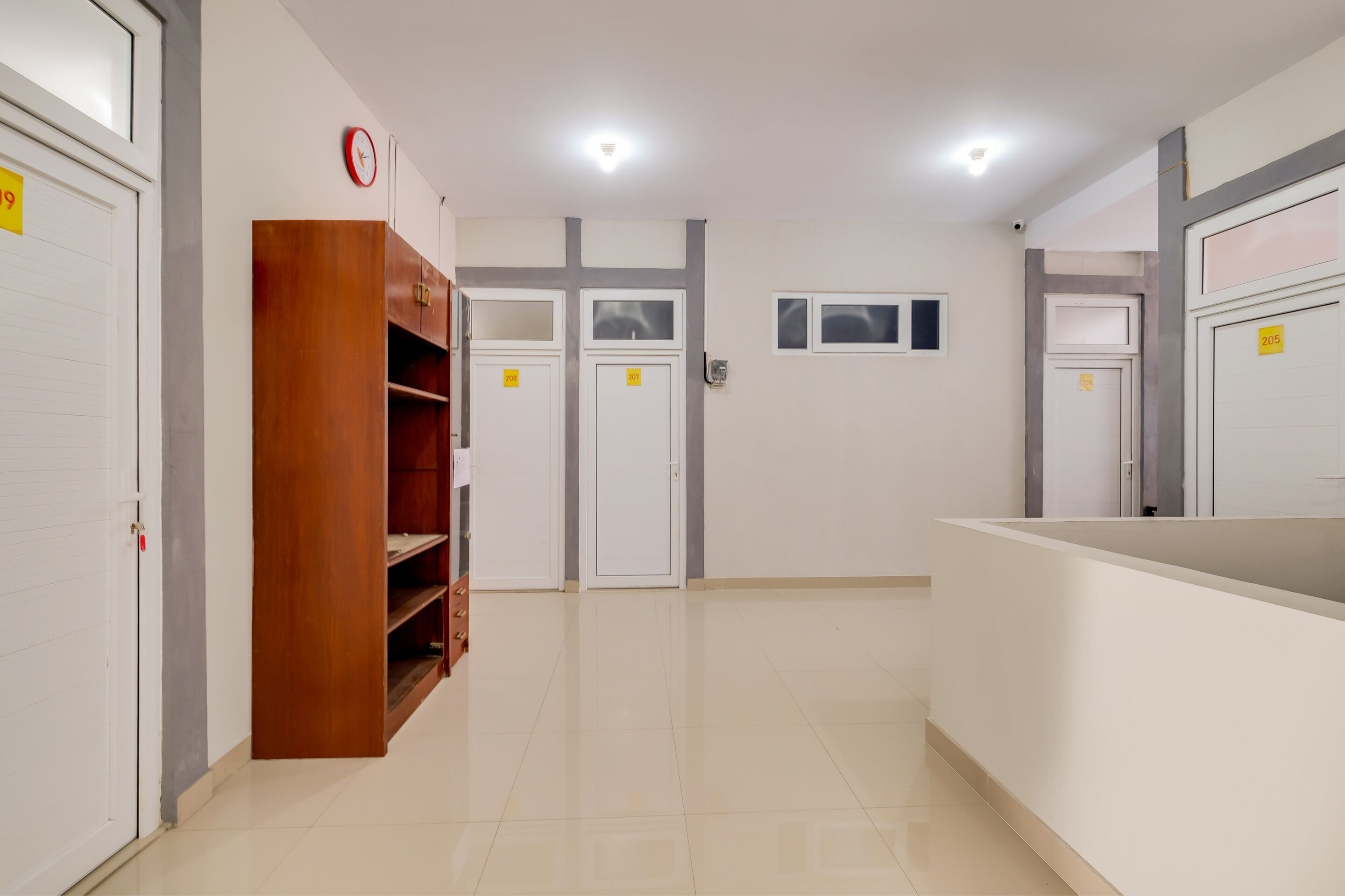 A hotel corridor with white doors, a wooden wardrobe, and a reception desk.