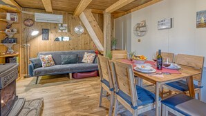 Un ambiente accogliente in legno, con divano, tavolo da pranzo, sedie e camino.