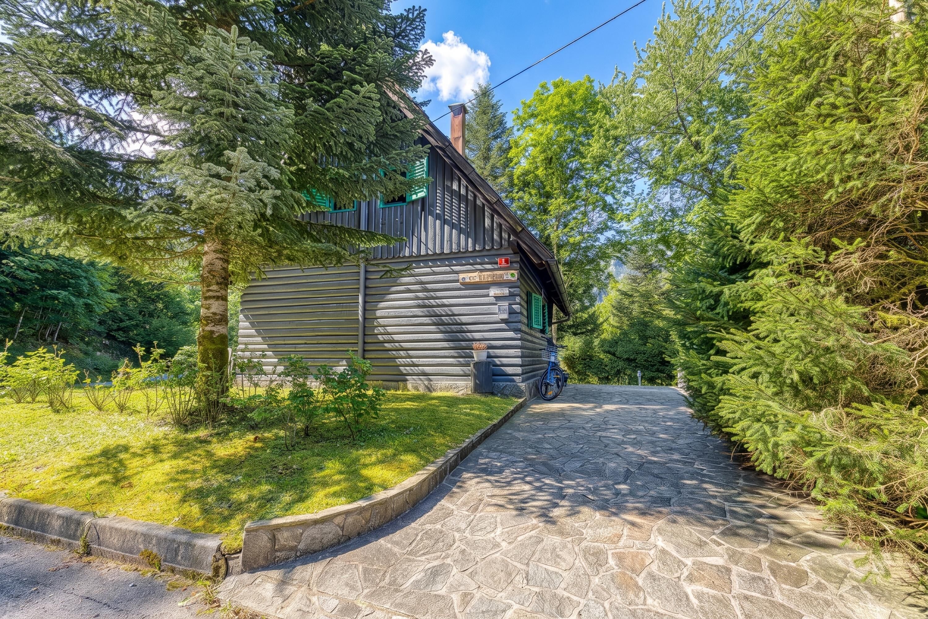 Eine Blockhütte mit einem Kiesweg, der zum Eingang führt, umgeben von dichtem Grün.