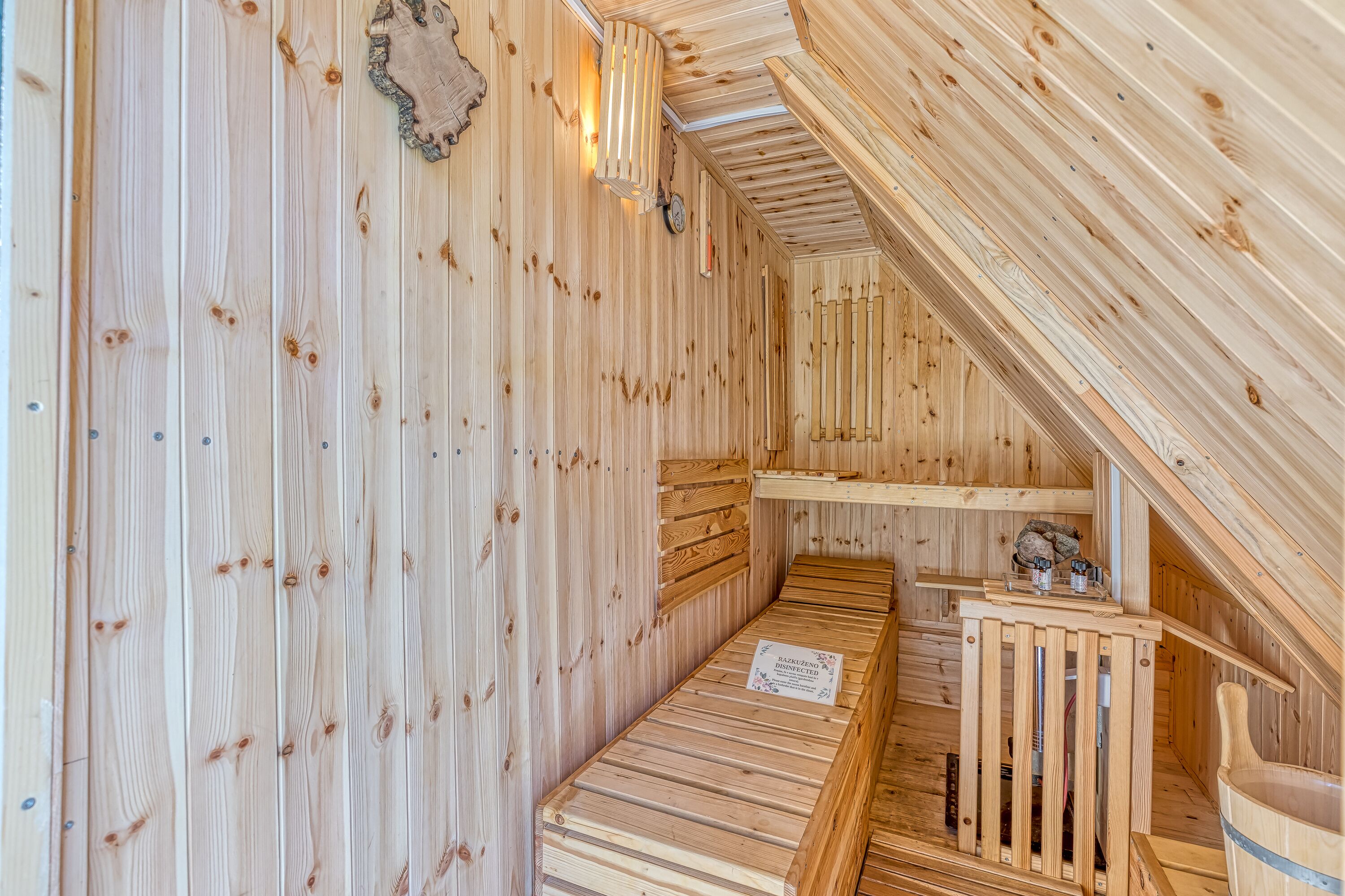 Eine Holzsauna mit geneigter Decke, Holzsitzen und einem Holzeimer.