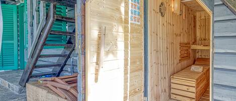 Un sauna en bois, avec un banc en bois et une échelle menant à une mezzanine.