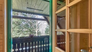 Una baita di legno con un portico dotato di ringhiera decorativa e una porta in vetro con maniglia metallica.