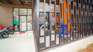 A modern interior with a glass door entrance, a motorcycle parked outside, and a seating area visible through the door. - Collection O Millenium Inn 2 (Medan)