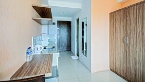 A modern kitchen with a wooden countertop, a sink, and a coffee maker. There is a door leading to another room and a wardrobe with a wooden finish. - Hotel O Tridasa (Medan)