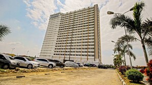 A tall hotel with multiple floors and a parking lot in front. - Hotel O Tridasa (Medan)