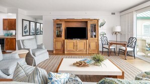 Un salón amplio con un televisor grande, asientos cómodos y un comedor.