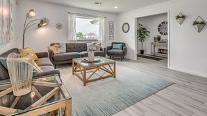 A modern living room with a sofa, armchair, coffee table, and a large window. - Capital View - Downtown OKC 7 MINS AWAY (Oklahoma City)