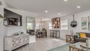 A modern living room with a dining area, a sofa, a coffee table, and a decorative cabinet. - Capital View - Downtown OKC 7 MINS AWAY (Oklahoma City)