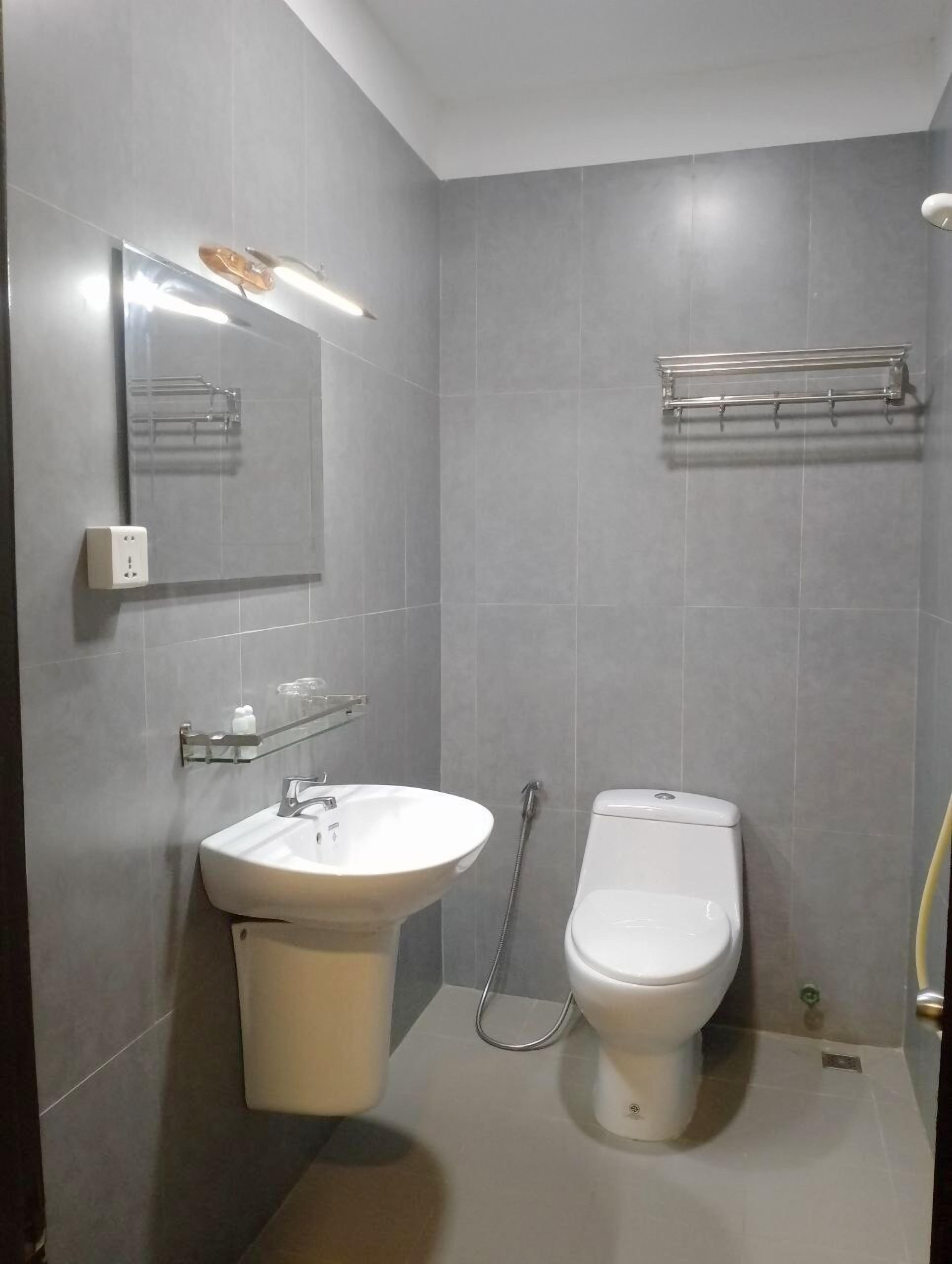 A modern bathroom with a white sink, a toilet, and a towel rack on the wall.