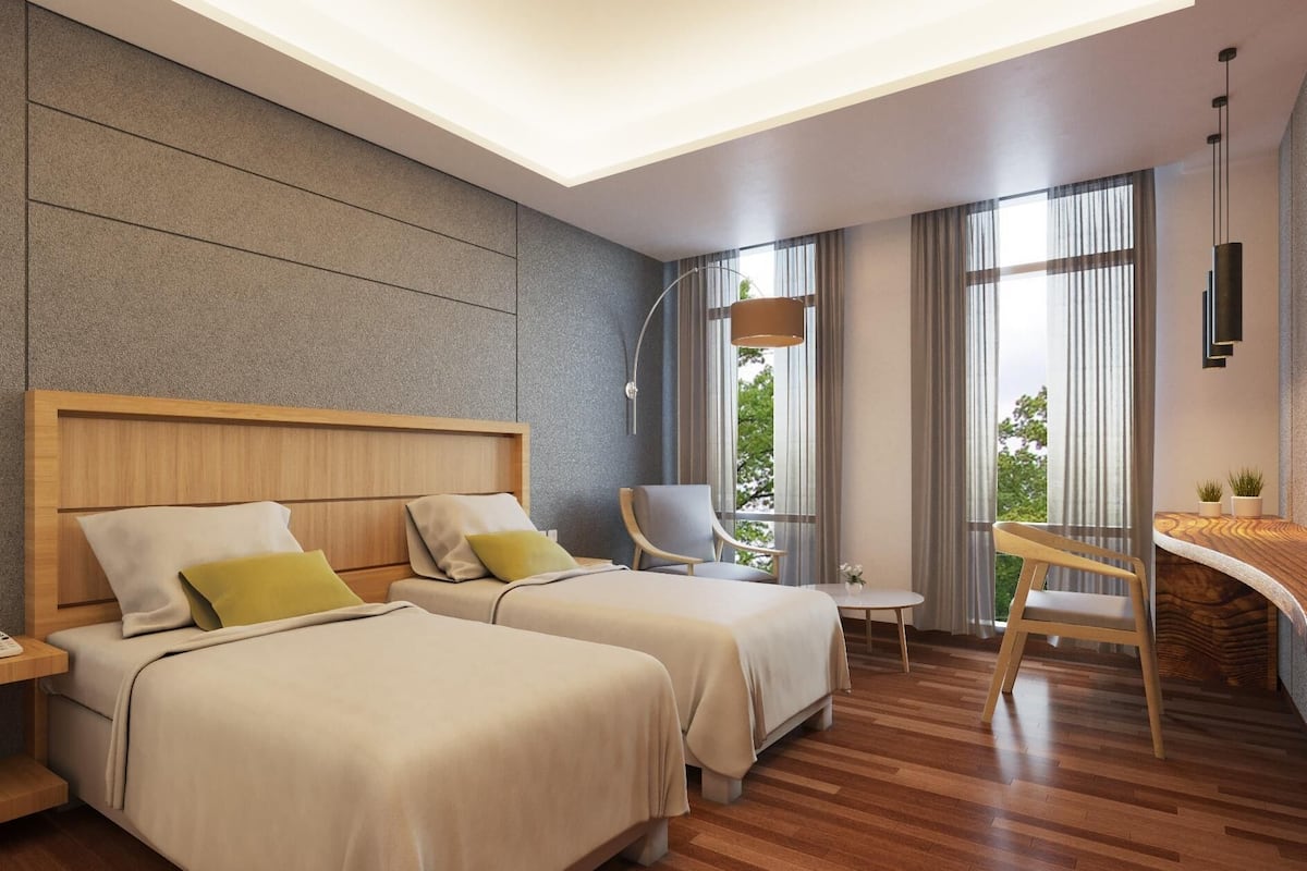 A modern hotel room with two beds, a desk, a chair, and large windows.