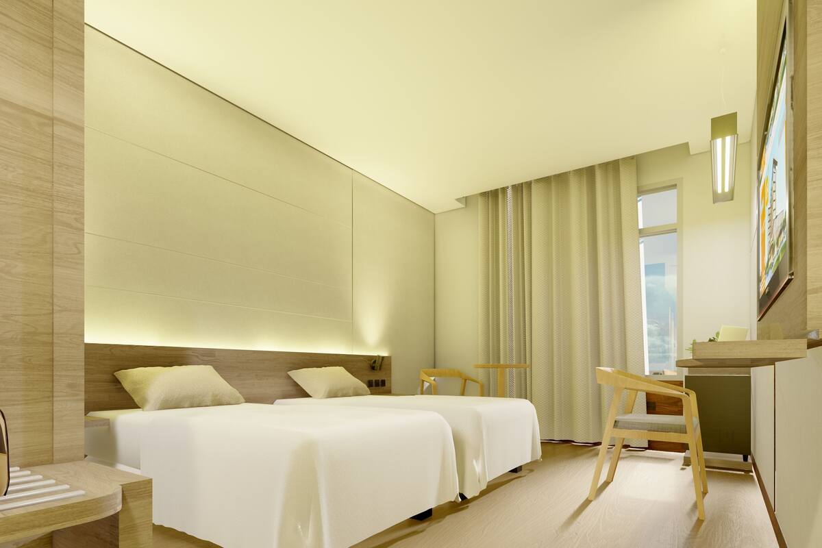 A hotel room with two beds, a desk, a chair, a window with curtains, and a painting on the wall.