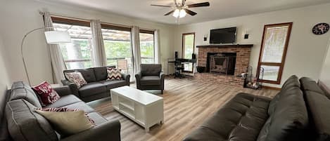 A living room with a fireplace, a ceiling fan, and a TV.