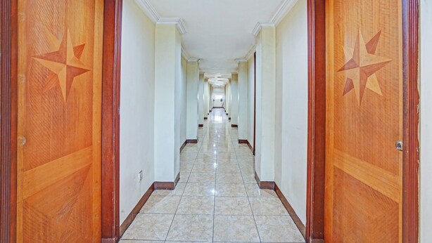 A long, narrow hallway with wooden doors on either side, leading to a bright room at the end. - OYO Life 90380 Andalus Hotel Syariah (Surabaya)