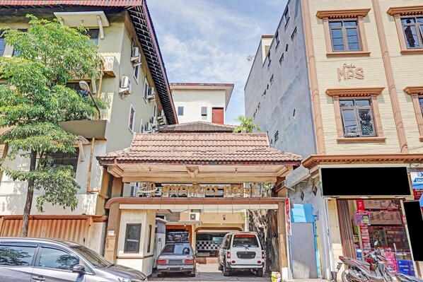 A hotel entrance with a tiled roof, a Mitsubishi van parked outside, and a tree to the left. - OYO Life 90380 Andalus Hotel Syariah (Surabaya)