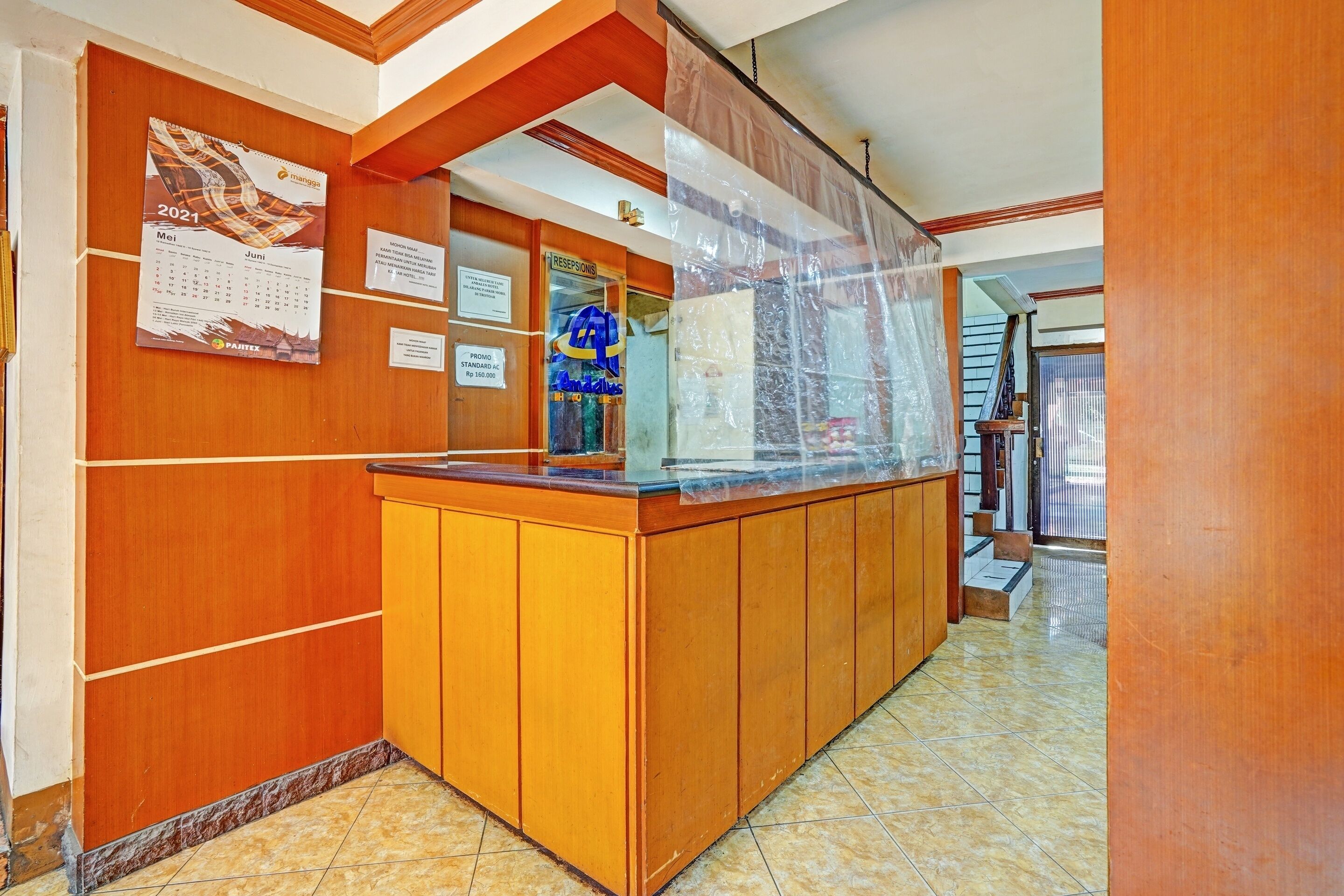 A reception area with a wooden counter, a calendar, and a sign indicating a reception desk.
