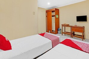 A hotel room with two beds, a wooden wardrobe, a small desk, and a television. - OYO Life 90380 Andalus Hotel Syariah (Surabaya)