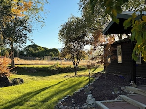 A wooden cabin with a stone bear statue holding a sign, surrounded by a well-maintained lawn and trees.
