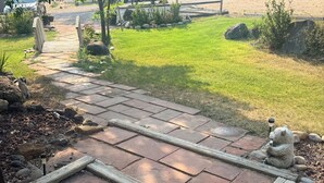 A paved pathway with wooden borders, a grassy area, and a vehicle in the background.