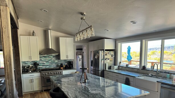 A modern kitchen with a large island, stainless steel appliances, and a view of the outdoors.