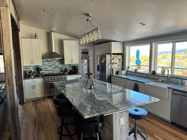 A modern kitchen with a large island, stainless steel appliances, and a view of the outdoors.