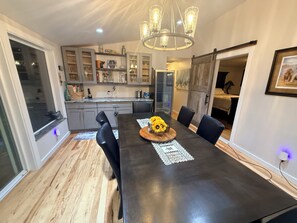 A modern dining area with a dark wooden table, black chairs, and a chandelier. - Beautiful River property with beach access. Relaxing deck-overlooking the valley (New Castle)