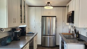 A compact kitchen with white cabinets, a stainless steel refrigerator, a coffee maker, and a microwave.