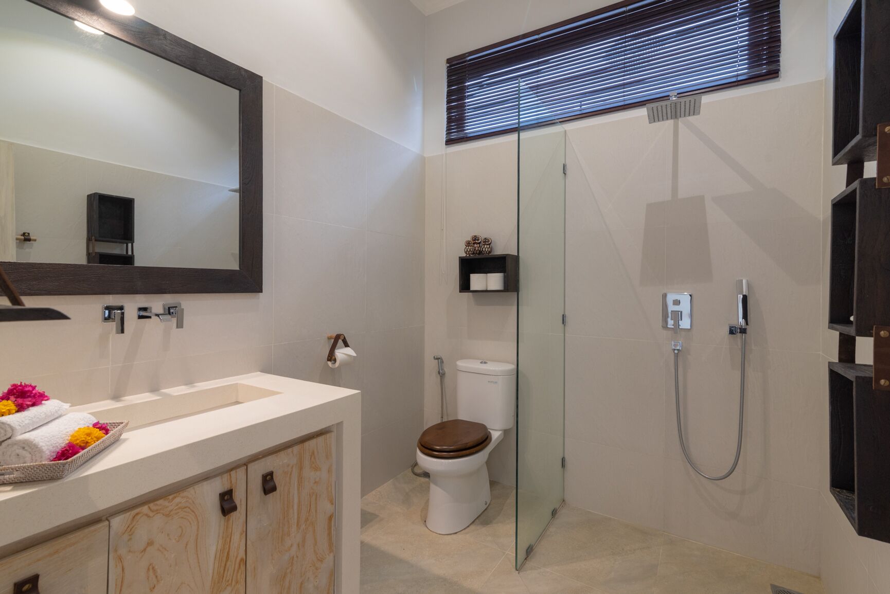 A modern bathroom with a glass-enclosed shower, a toilet, and a vanity with a mirror.