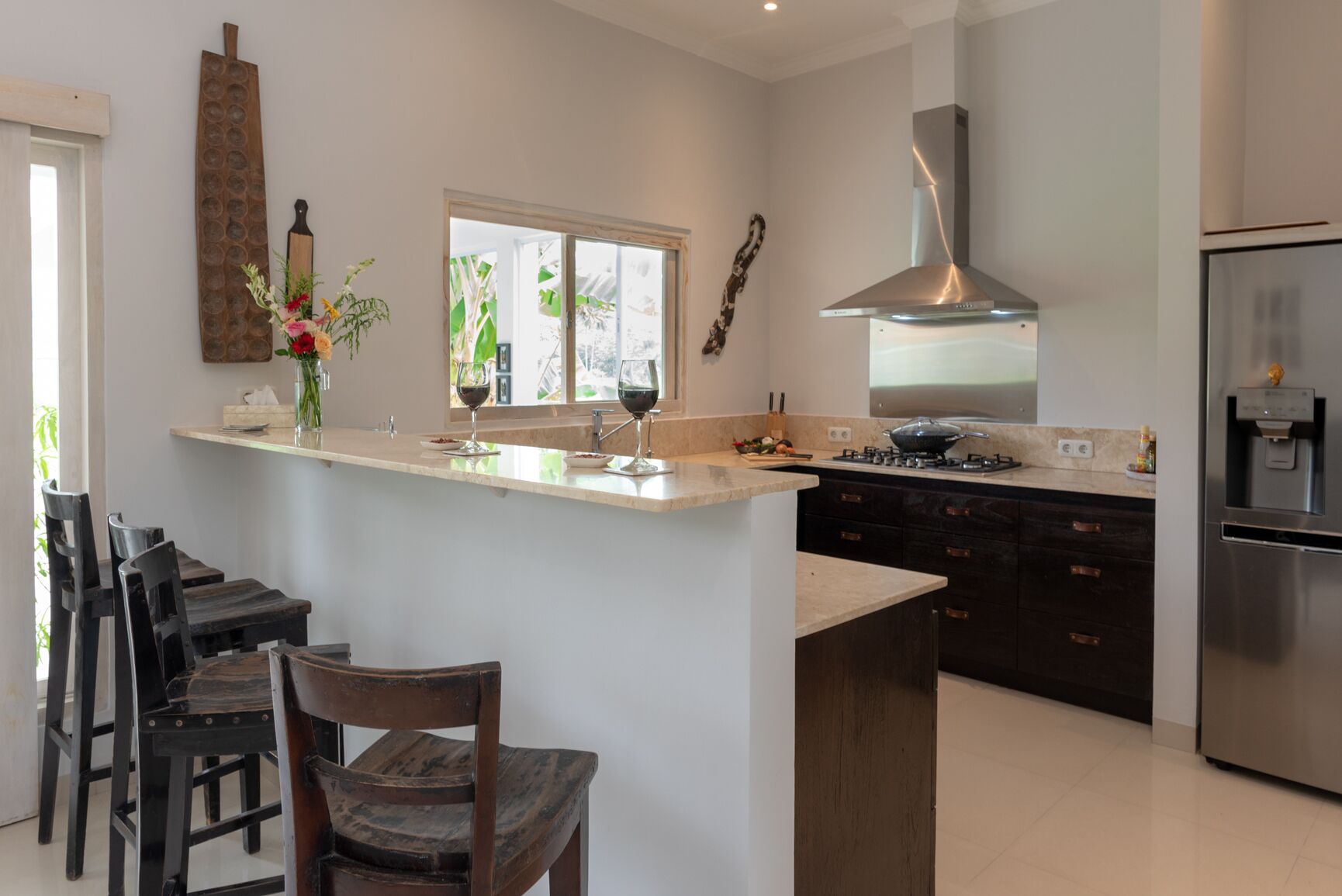 A modern kitchen with a central island, a built-in stove, and a stainless steel refrigerator.