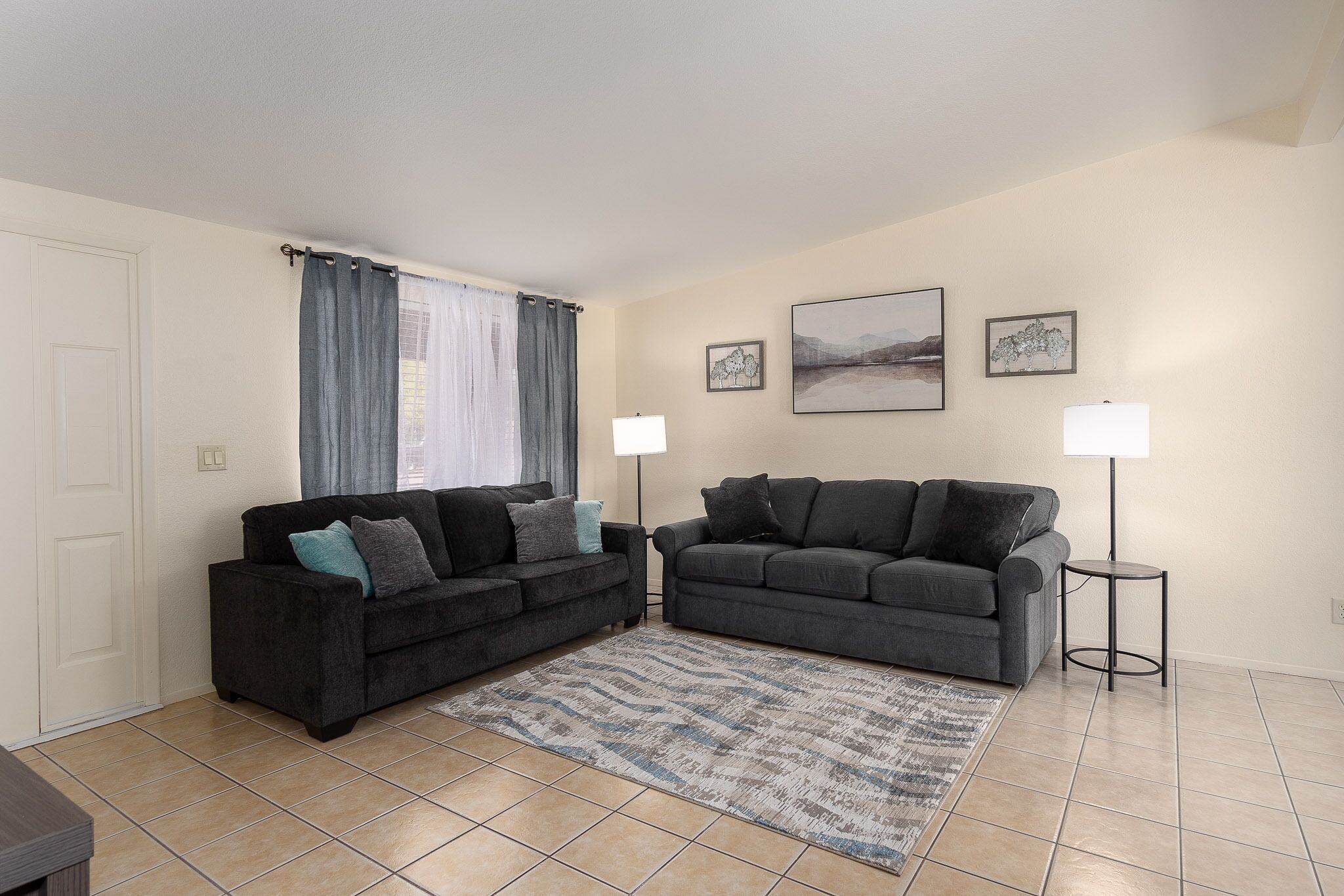 A living room with two dark grey sofas, a patterned rug, and two floor lamps.