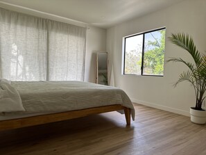 Relax in a serene space with a large bed, natural views, and a potted plant.