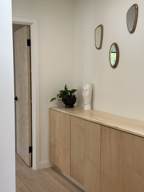 Stylish hallway with a wooden cabinet, mirrors, and a door leading to a separate space.