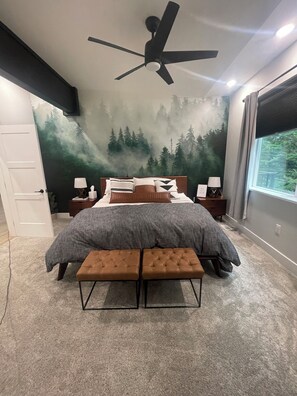 A bedroom with a bed, two nightstands, a bench, a ceiling fan, a forest mural, and a window. - 4th night FREE- Ski Condo with Hot Tub & Sauna (Girdwood)