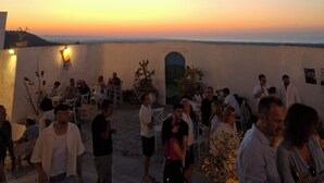 Reunión en la azotea con gente, un atardecer y un edificio blanco con una puerta.