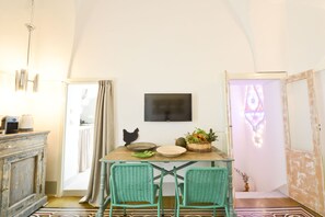 A dining area with a table, chairs, a television, and a decorative basket. - L'Angolo di Ostuni (Ostuni)