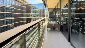 Ein modernes Gebäude mit großen Glasfenstern, einem Balkon mit Korbmöbeln und freiem Blick zum Himmel.