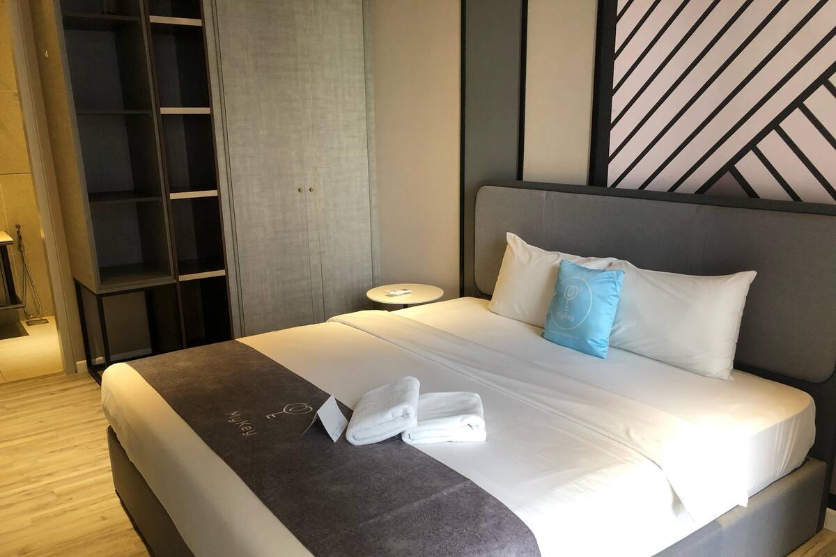 Una habitación de hotel con cama, toalla, mesita de noche y armario.