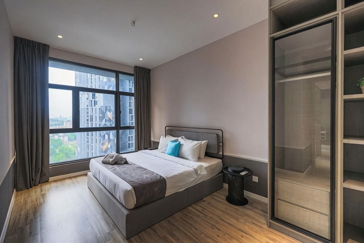 Un dormitorio moderno con un ventanal grande, una cama, un armario y un cubo de basura pequeño.